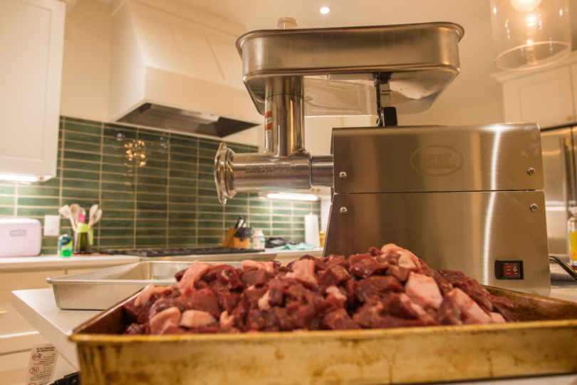 The LEM Meatgrinder with meat in front of it.