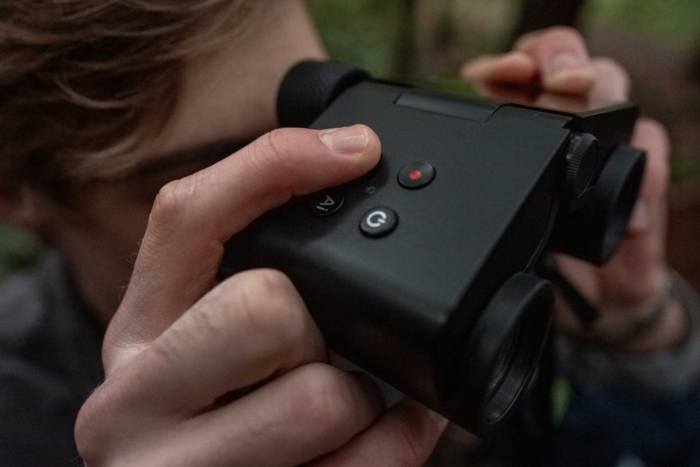 A person using the Solvia ED binoculars, with a close view of the control buttons while looking through them