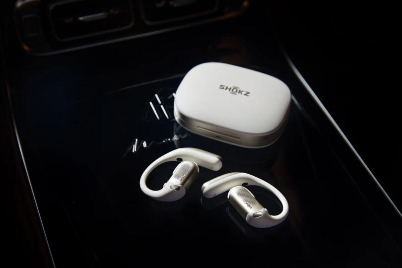 OpenFit Pro earbuds and the charging case are placed on a dark glass surface