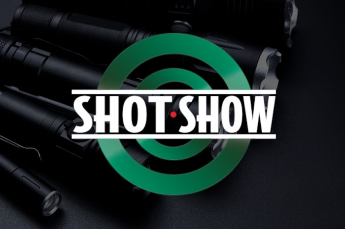 An image with a shot show logo with flashlights in the background.