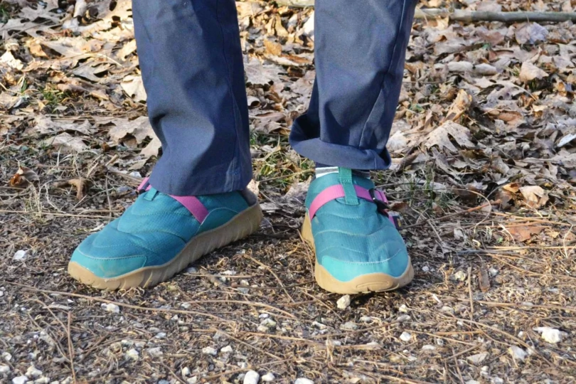 close up shot of person wearing outdoor slippers in woods