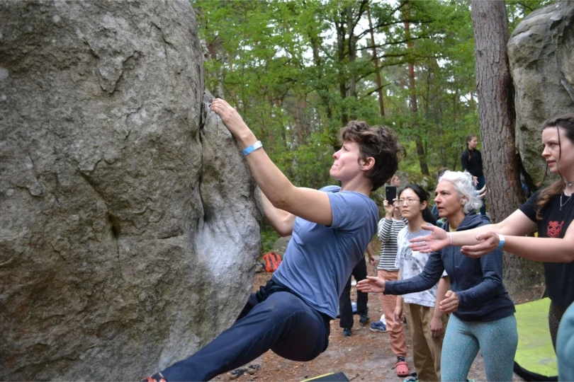 person bouldering with people spotting