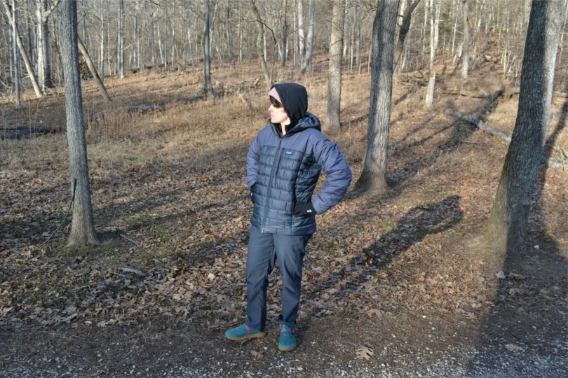 person stands in woods in winter clothes