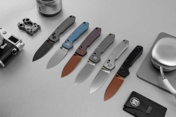 Several Vosteed Racoon TiSlim knives displayed open, showing different handle and blade finishes
