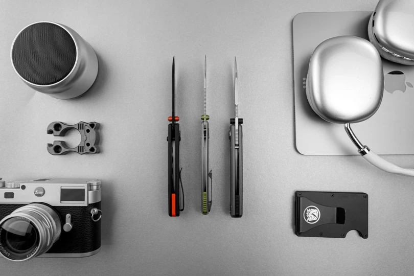 Three Racoon TiSlim knives standing upright, showing spine thickness and pocket clips