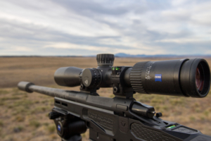 The Zeiss Conquest V4 riflescope mounted on a rifle overlooking a vast landscape.
