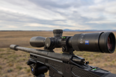 The Zeiss Conquest V4 riflescope mounted on a rifle overlooking a vast landscape.