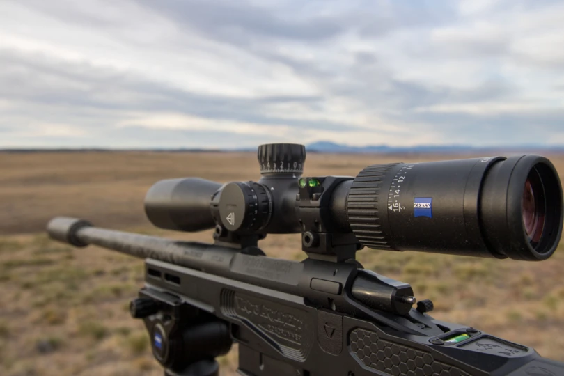 The Zeiss Conquest V4 riflescope mounted on a rifle overlooking a vast landscape.