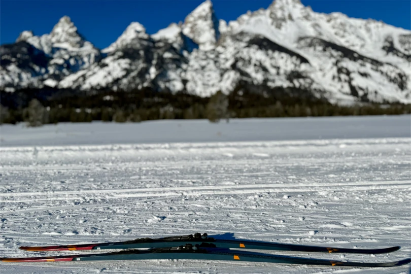 The Aeroguide 85s lie flat on snow with a blurred mountain range in the background