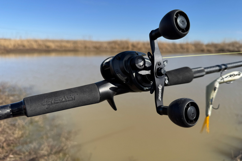 Close-up of the Beast baitcasting combo reel and oversized handle knobs beside the water