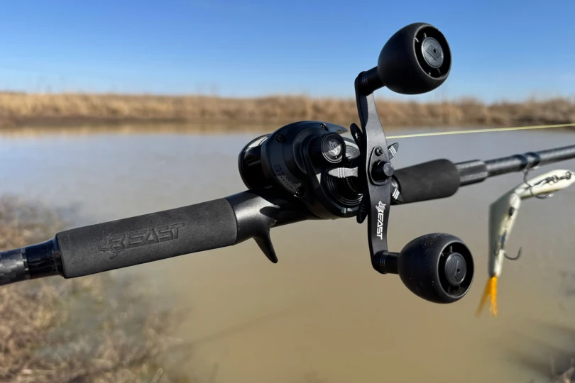 Close-up of the Beast baitcasting combo reel and oversized handle knobs beside the water