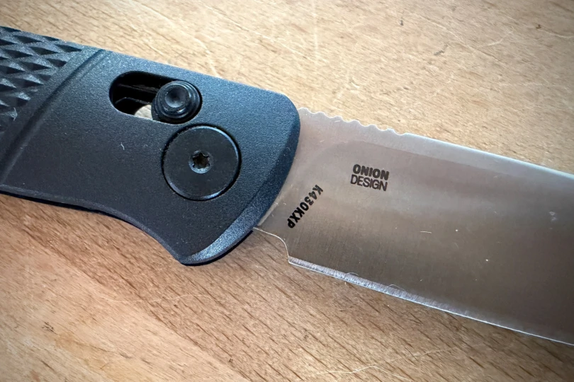 Close-up of the knife blade showing the Onion Design logo and the steel marking near the handle