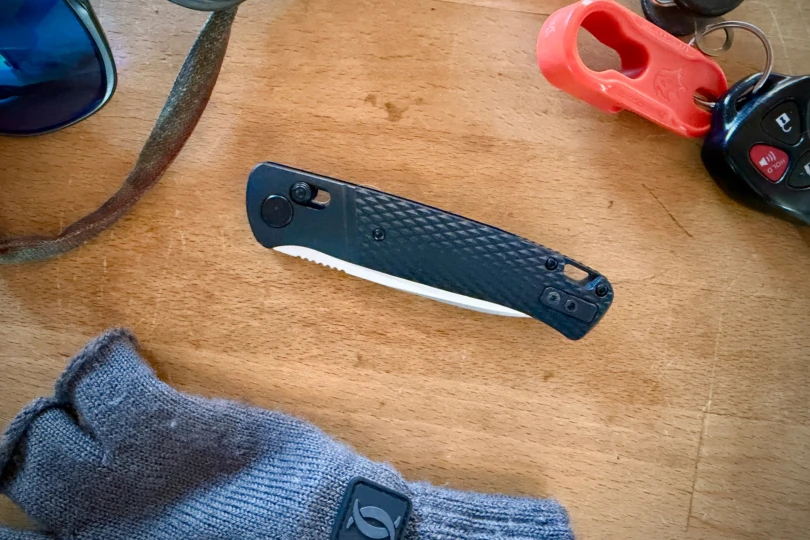The knife closed on a table next to keys, sunglasses, and gloves