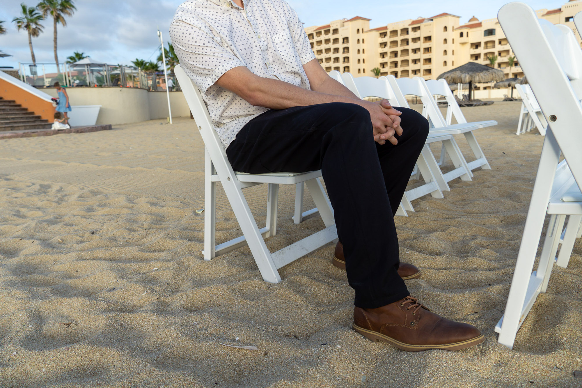 the author wearing the unbound merino travel pants on a beach in cabo san lucas at a wedding