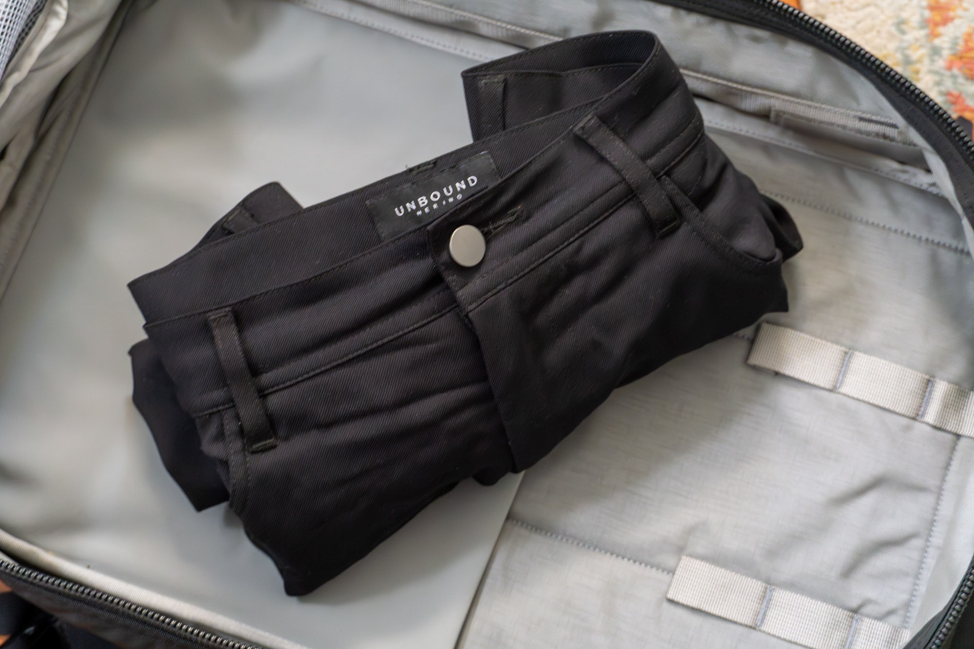 the rolled up unbound merino travel pants in a backpack