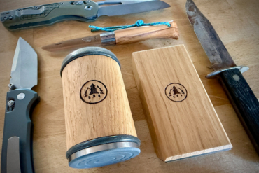 The rolling sharpener and angle block are placed among several knives on a wooden table