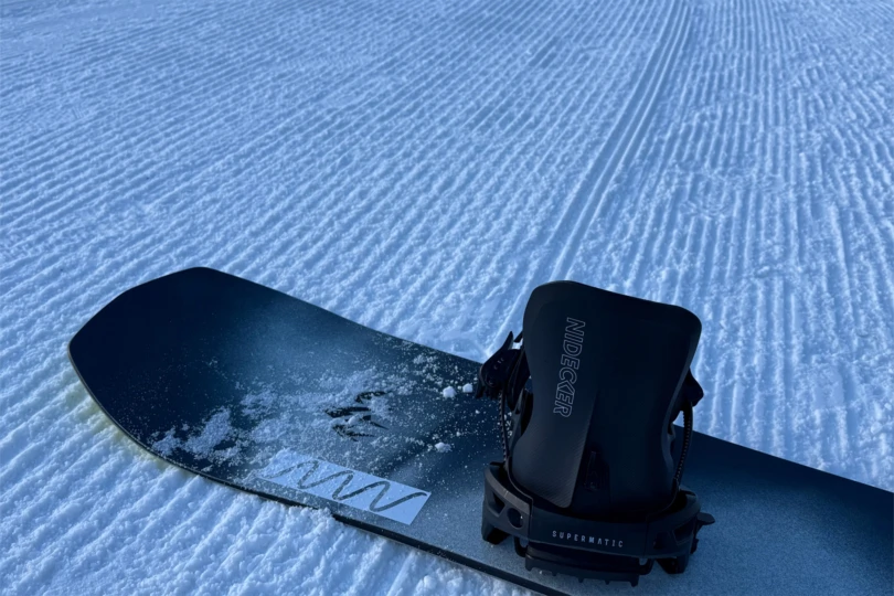 The Nidecker LT Supermatic sits mounted on a snowboard over freshly groomed snow