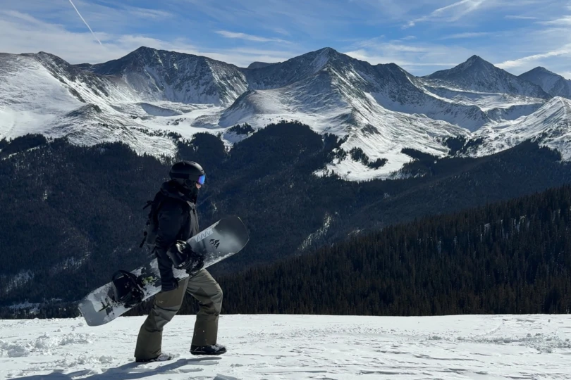 The rider stands with the Nidecker LT Supermatic bindings overlooking snowy peaks