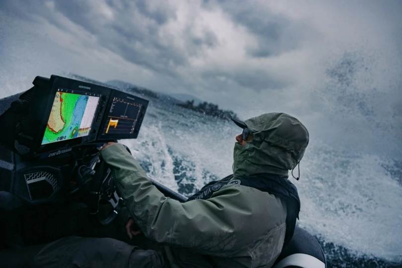 An angler driving a boat in stormy conditions.