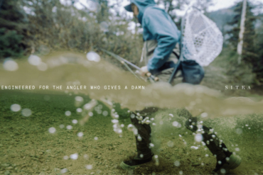 A photo half in and half out of the water showing an angler wading through a river.