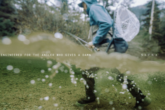 A photo half in and half out of the water showing an angler wading through a river.