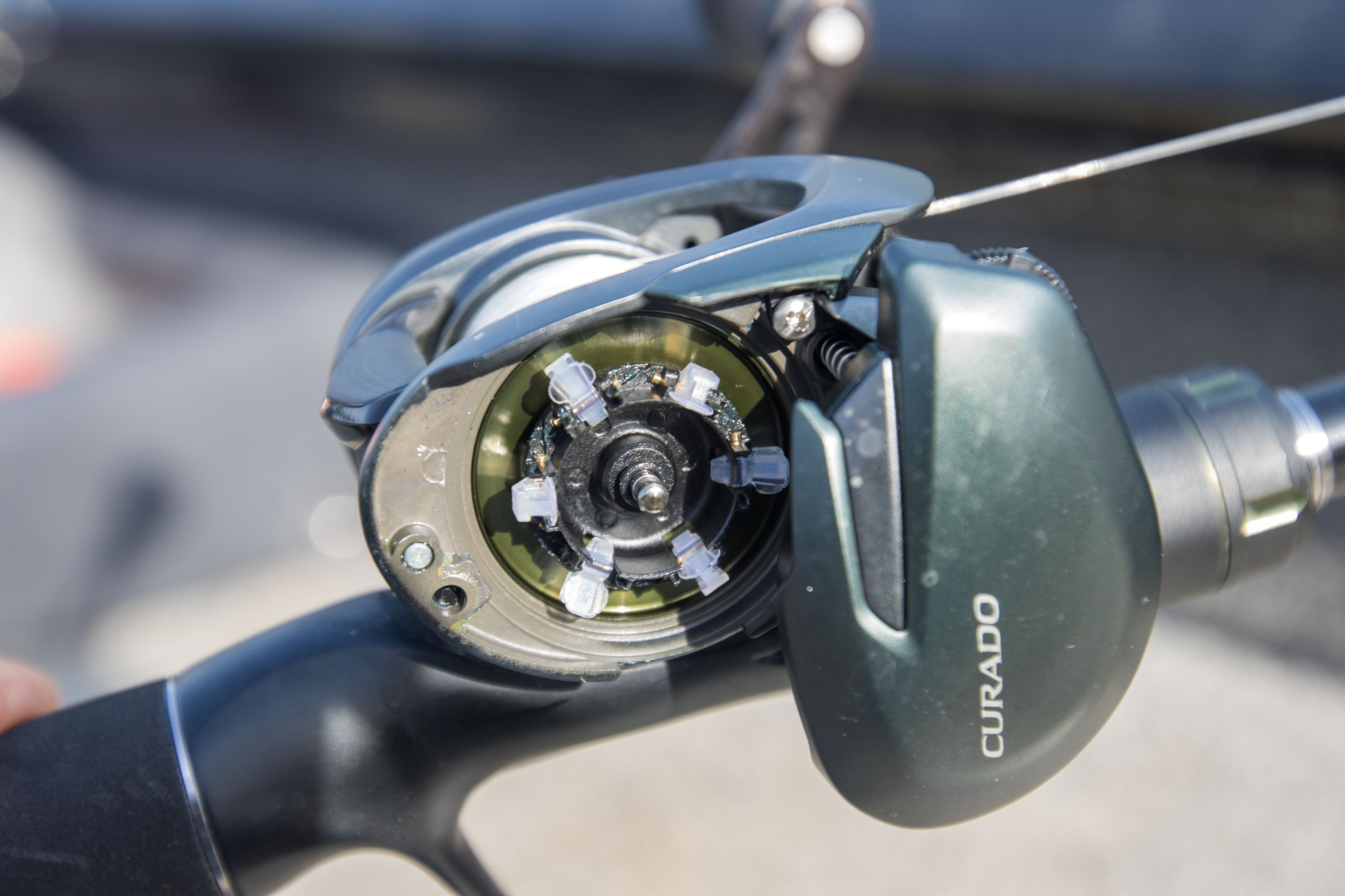 The Shimano Curado 150M with the side plate open, exposing the brake system.