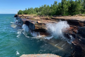 blue waves crash onto rocky formation on shore