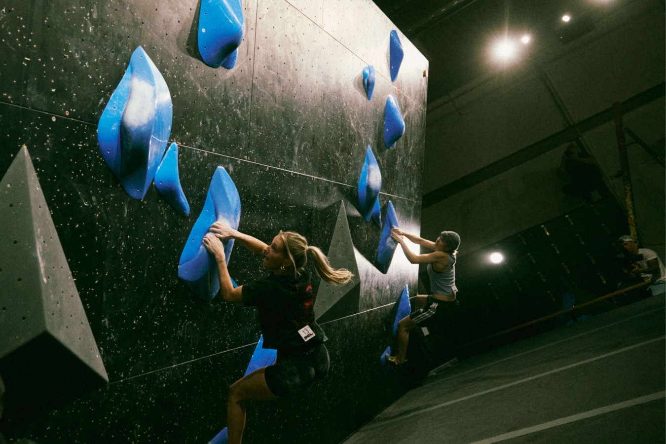 two climbers climb the same boulder side by side