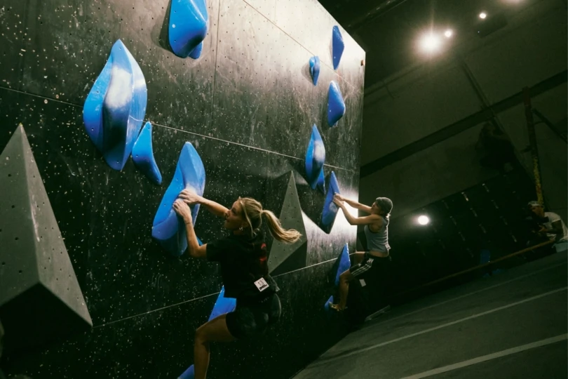 two climbers climb the same boulder side by side