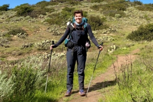 hiker standing on trail with poles and pack