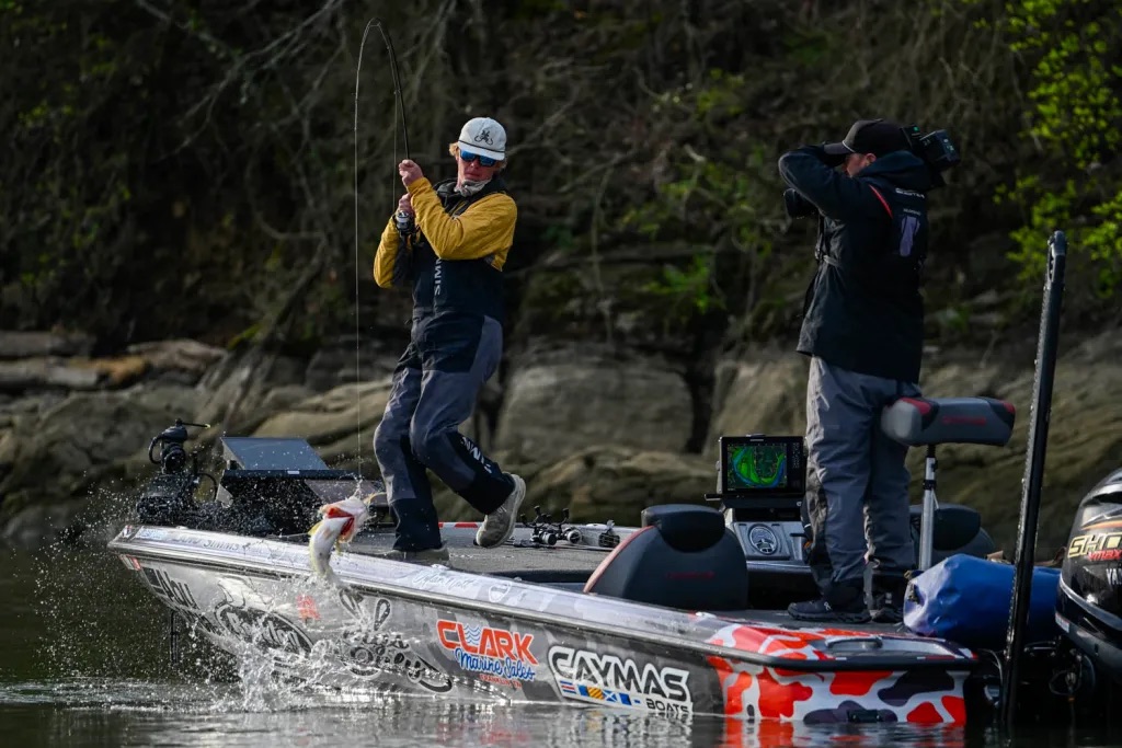 An angler lifting a bass into a boat.