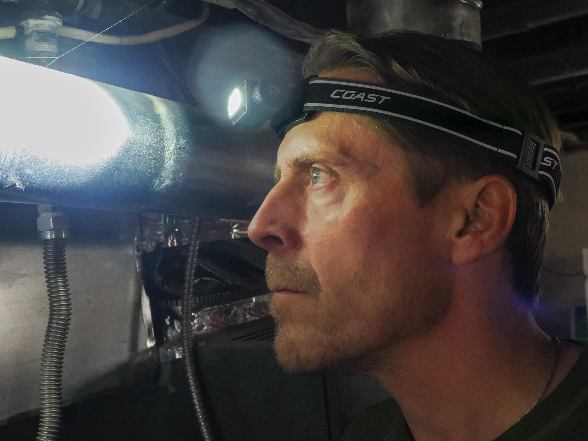 Man using Coast WPH10R Headlamp in basement