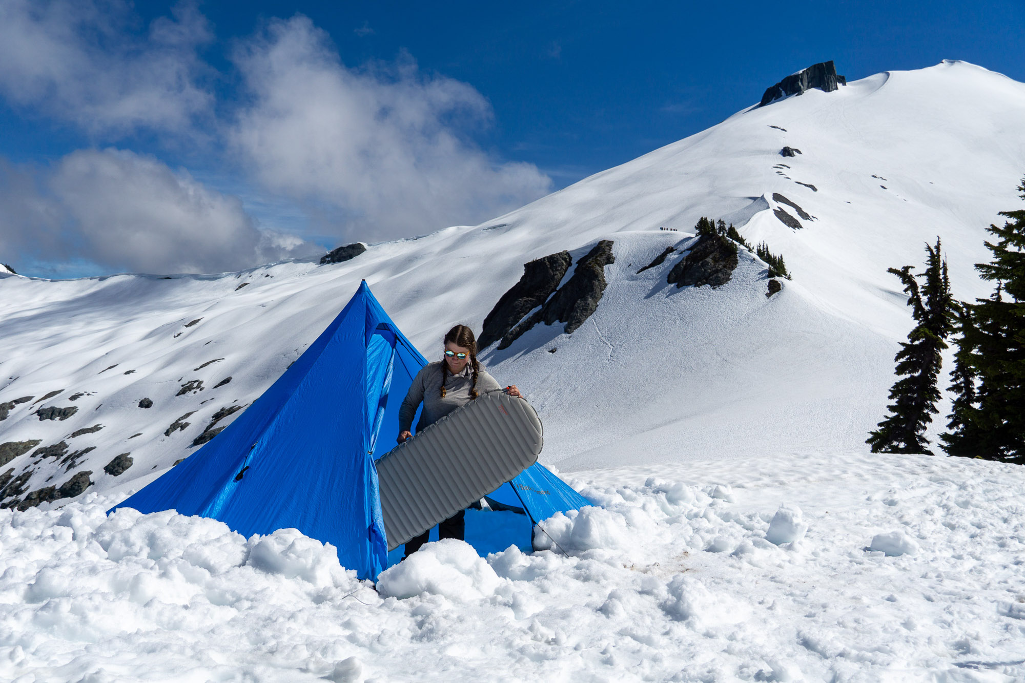 a backpacker sets up her pad in a snow camp