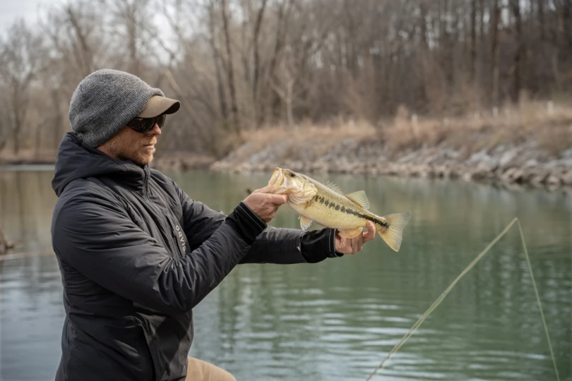 A fly fisherman holding a bass.