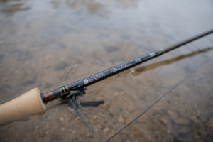 The Hardy Marksman Fly rod partially submerged in a river with a streamer on the hook keeper.