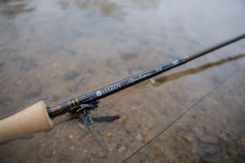 The Hardy Marksman Fly rod partially submerged in a river with a streamer on the hook keeper.