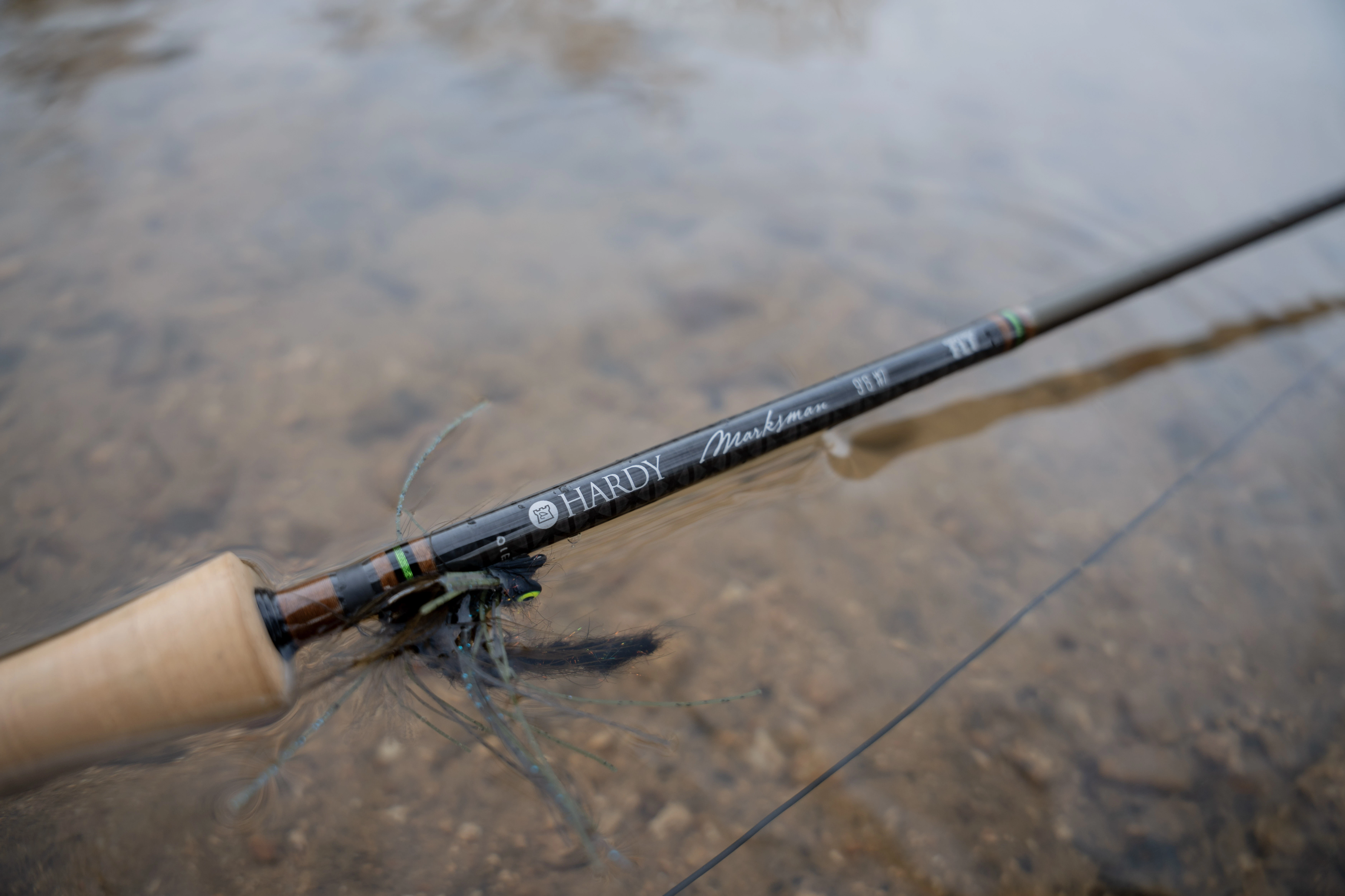 The Hardy Marksman Fly rod partially submerged in a river with a streamer on the hook keeper.
