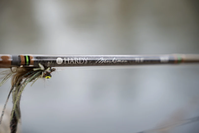 A bass fly next to the label on the Hardy Marksman fly rod.