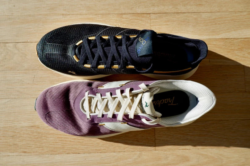 Two pairs of Tracksmith Eliot NDO running shoes shown from above on a wooden floor