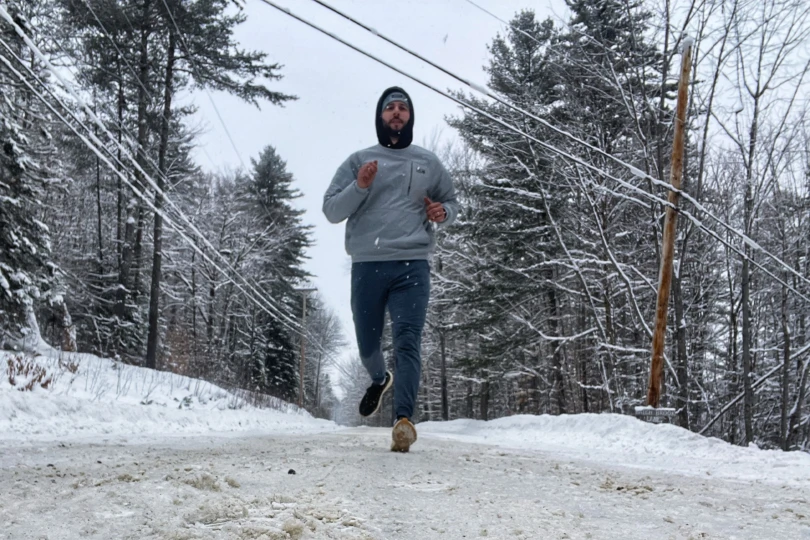 Runner wearing Tracksmith Eliot NDO shoes jogging along a snowy road