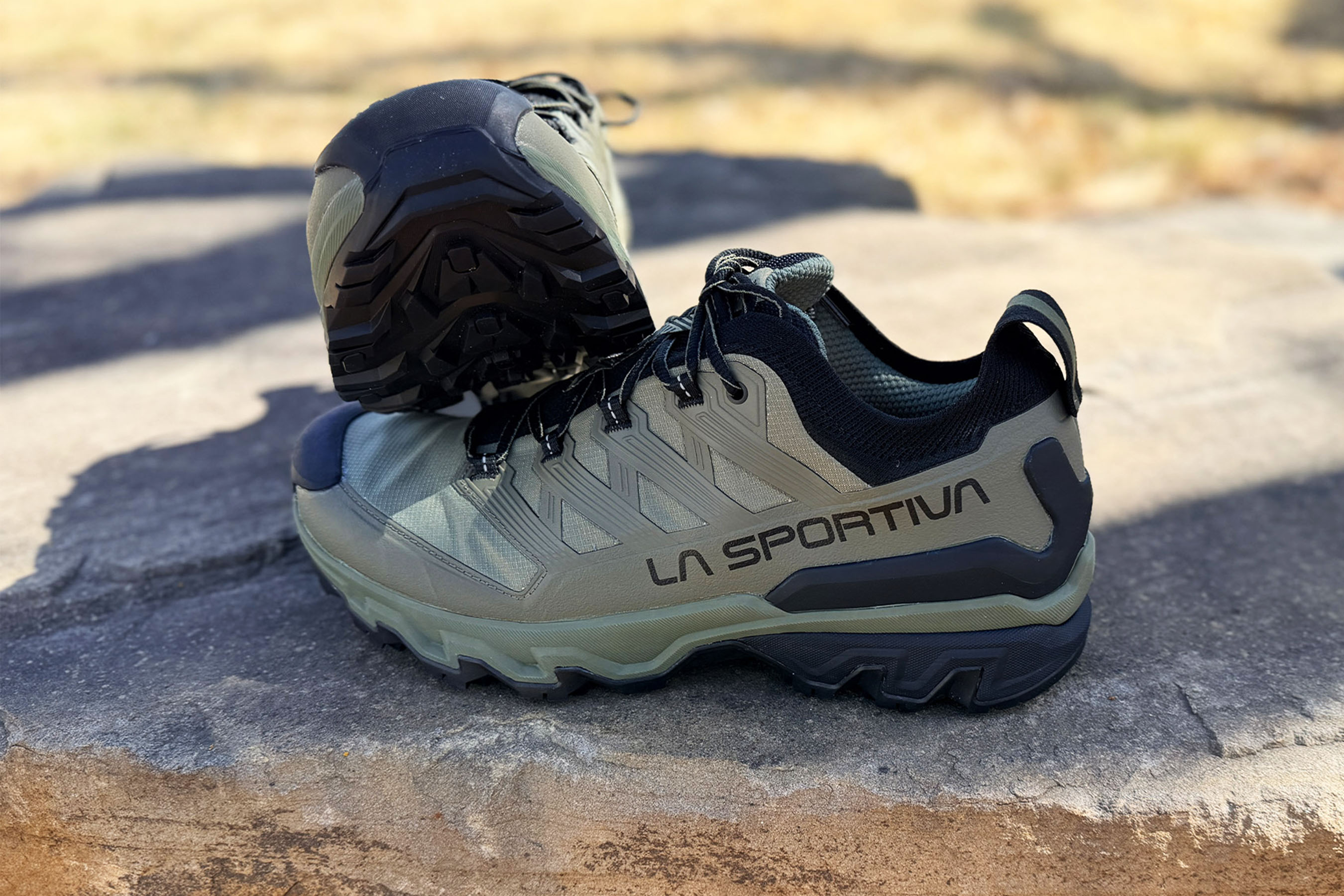 Trail running shoes showing aggressive outsole lugs and reinforced upper on rocky ground