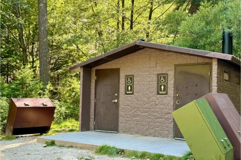 trail bathroom in the woods with garbage cans