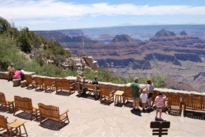 visitors lounge on overlook platform of grand canyon