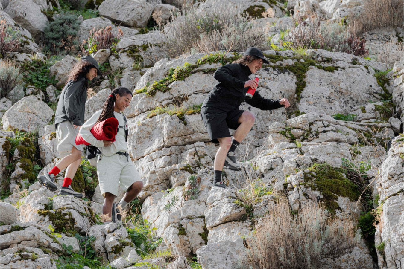three people hike across rocky trail