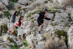 three people hike across rocky trail