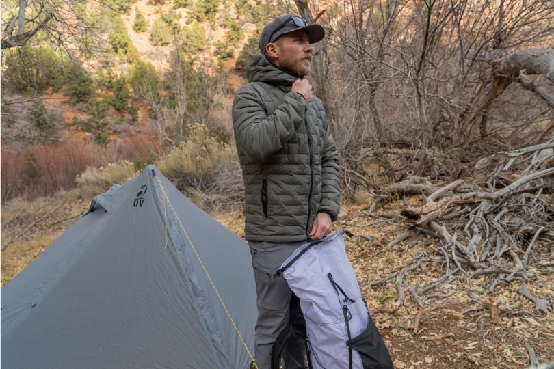 person zips up jacket outside tent