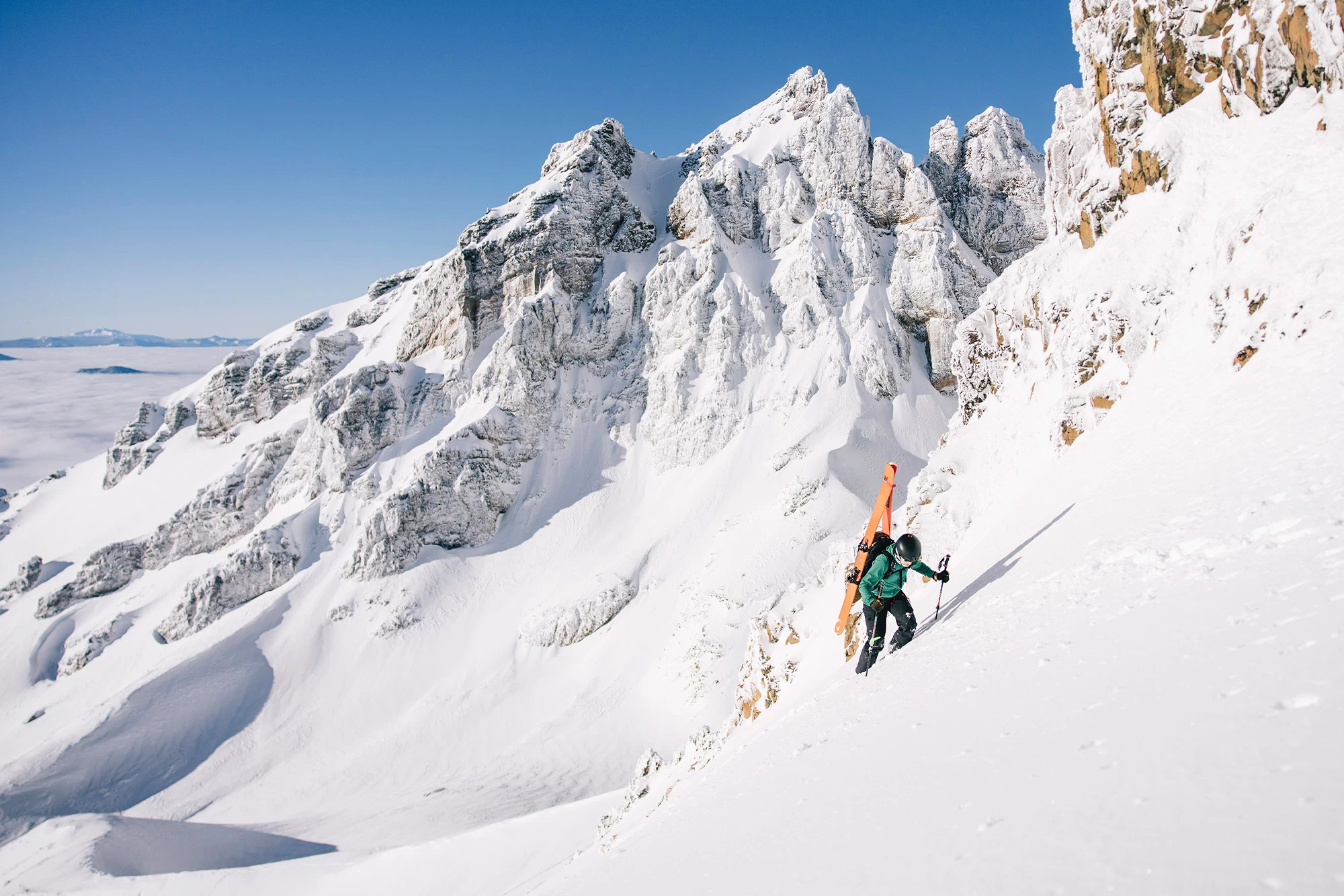 Skier climbing steep alpine terrain during spring volcano ski ascent