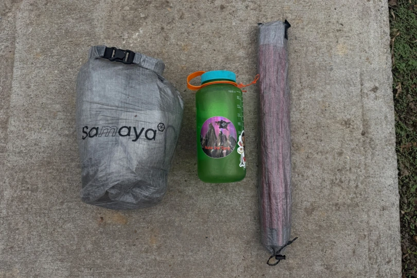 Packed Samaya tent next to a water bottle and pole bag for size reference