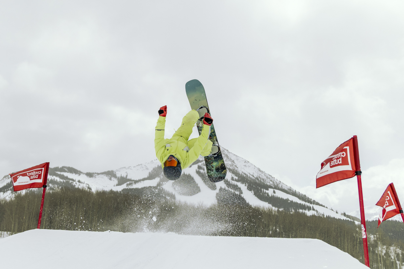 A rider flips upside down on the Burton Custom Flying V board during a jump on a snowy feature