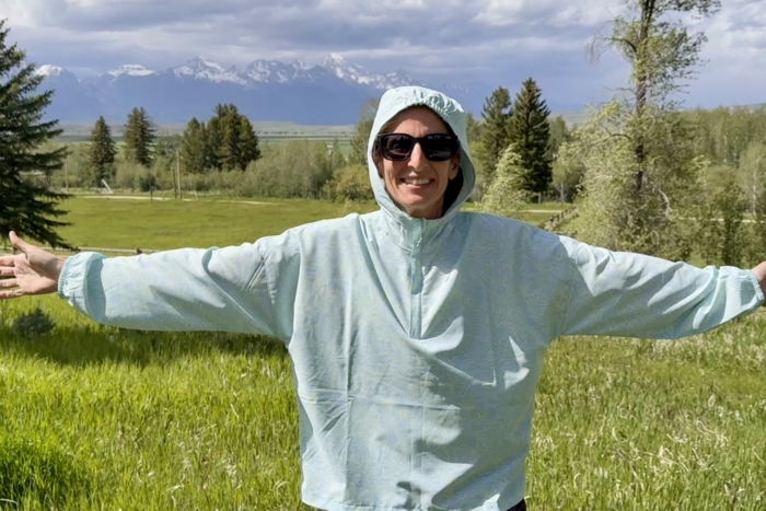 Woman showing the fit of a sun shirt with the hood up
